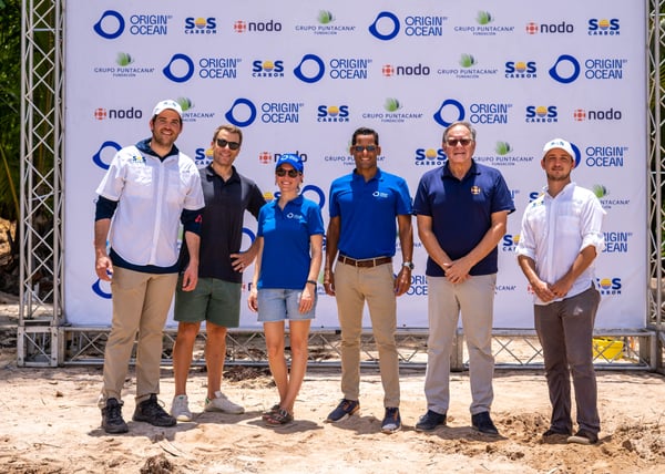 Group photo of Punta Cana project partners standing in front of an Origin by Ocean backdrop.