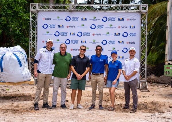  Another group Punta Cana photo of project partners in front of the Origin by Ocean backdrop with large bags visible in the background.